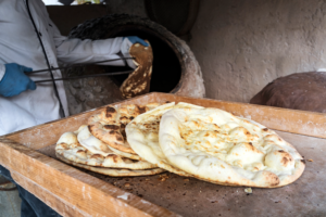 large-flat-freshly-baked-tortillas-lie-table-hot-bread-central-asian-cuisine-aged-man-makes-traditional-bread-old-round-stone-oven-rural-village